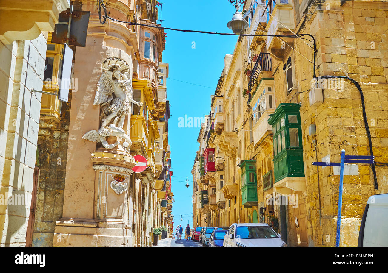 The niche or corner statues are very popular architectural detail in Valletta, such as statue of St Michael the Archangel, fighting the Satan, on corn Stock Photo