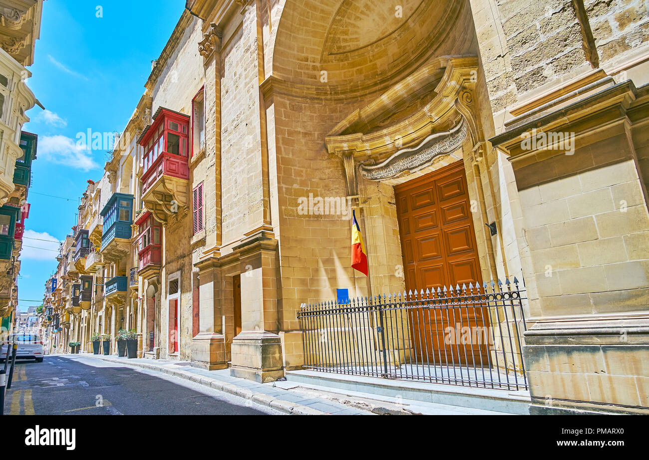 Ensemble of medieval St Ursula street includes the Baroque Church of St Roque and traditional edifices with bright Maltese balconies, Valletta, Malta. Stock Photo