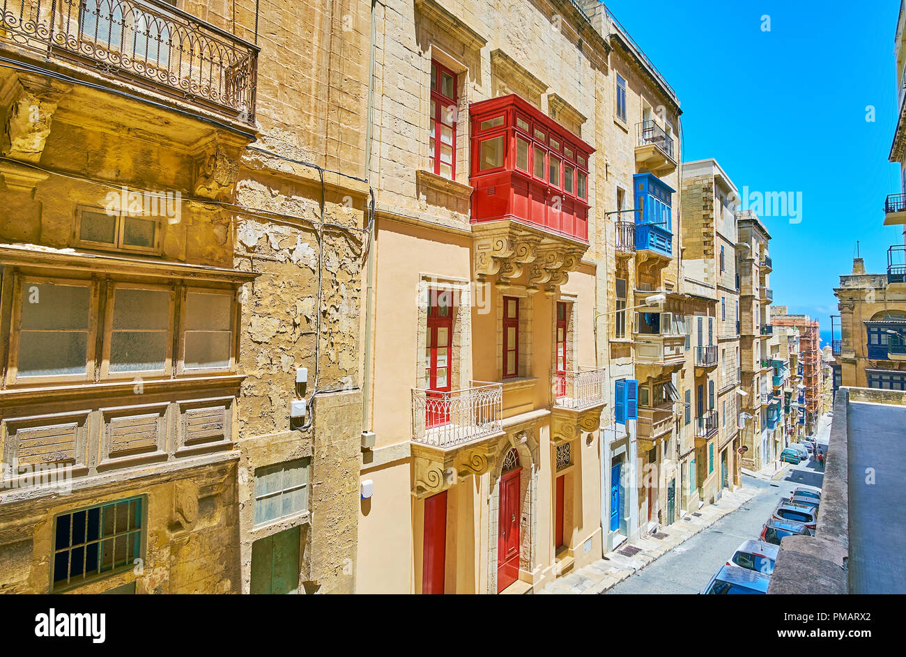 The view from the upper terrace on the gentle descent in St Ursula street with line of old edifices, with colored Maltese balconies, Valletta, Malta. Stock Photo
