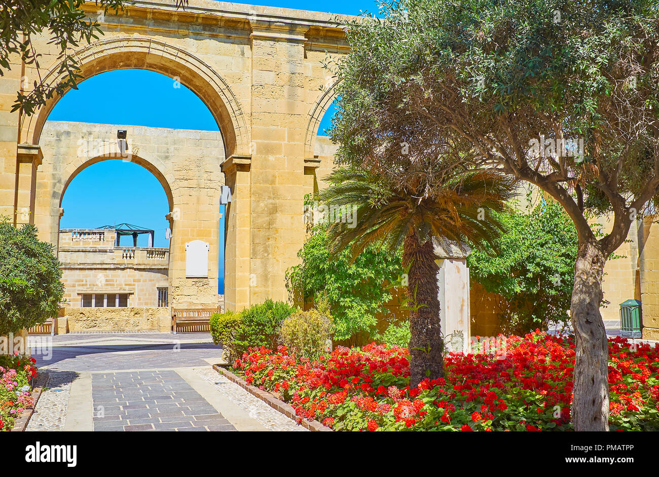 The bright flowers and shady greenery of Upper Barrakka Gardens with a view on its arched gallery, Valletta, Malta. Stock Photo