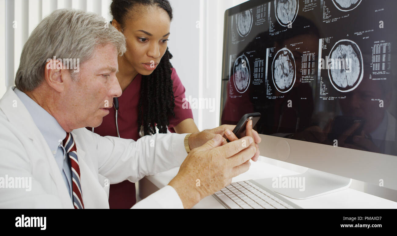 Two doctors analyzing brain xrays on computer Stock Photo