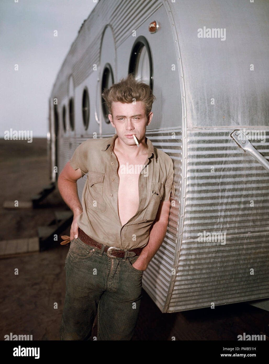 James Dean leaning against a dressing room trailer on the set of director George Stevens's film "Giant" 1955 Warner Bros.  File Reference # 33371_508THA Stock Photo