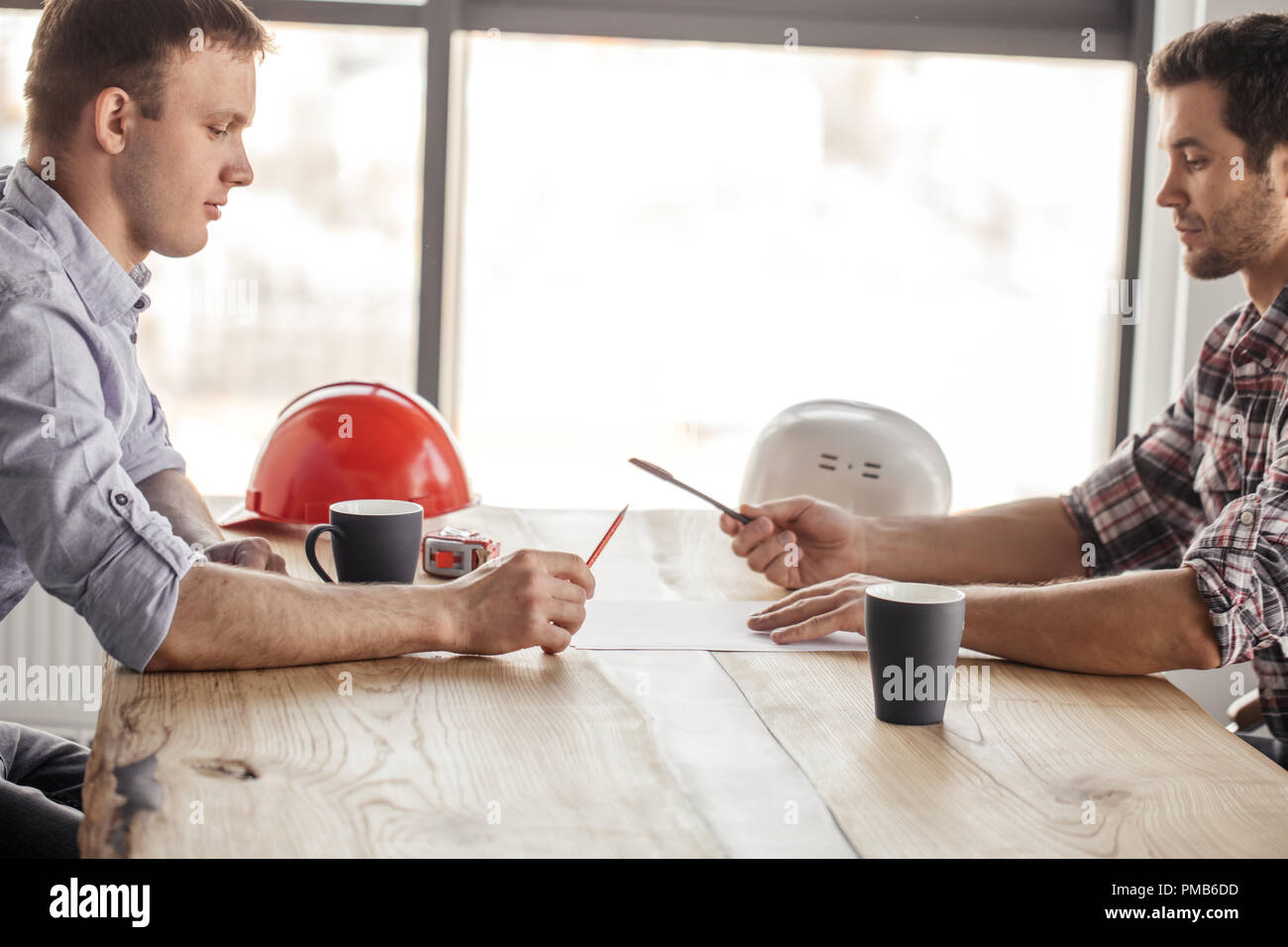 two architects are having fun with a pen and a pencil while drinking Stock Photo
