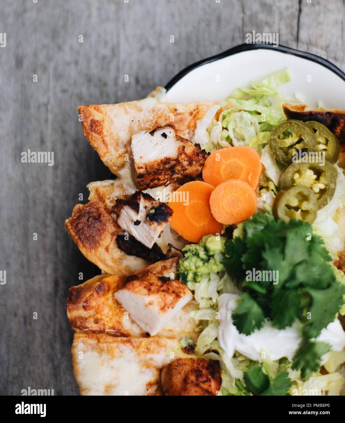 Tex-Mex meets fine dining with traditional texmex dishes including tamales, mole, quesadillas, and nachos on rustic tabletop with fresh toppings. Stock Photo