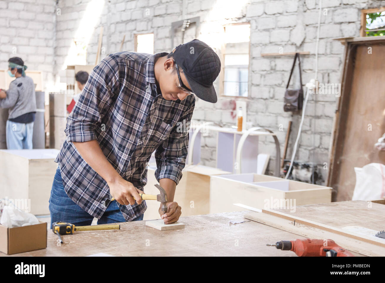worker at carpenter workspace installing nail using hammer Stock Photo