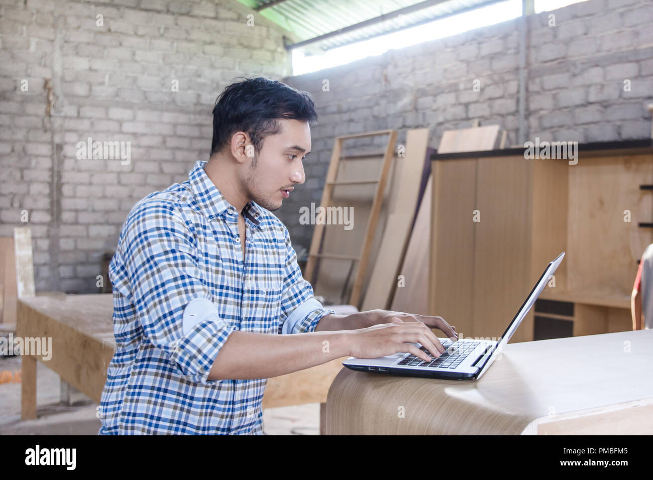 young carpenter working on his laptop Stock Photo