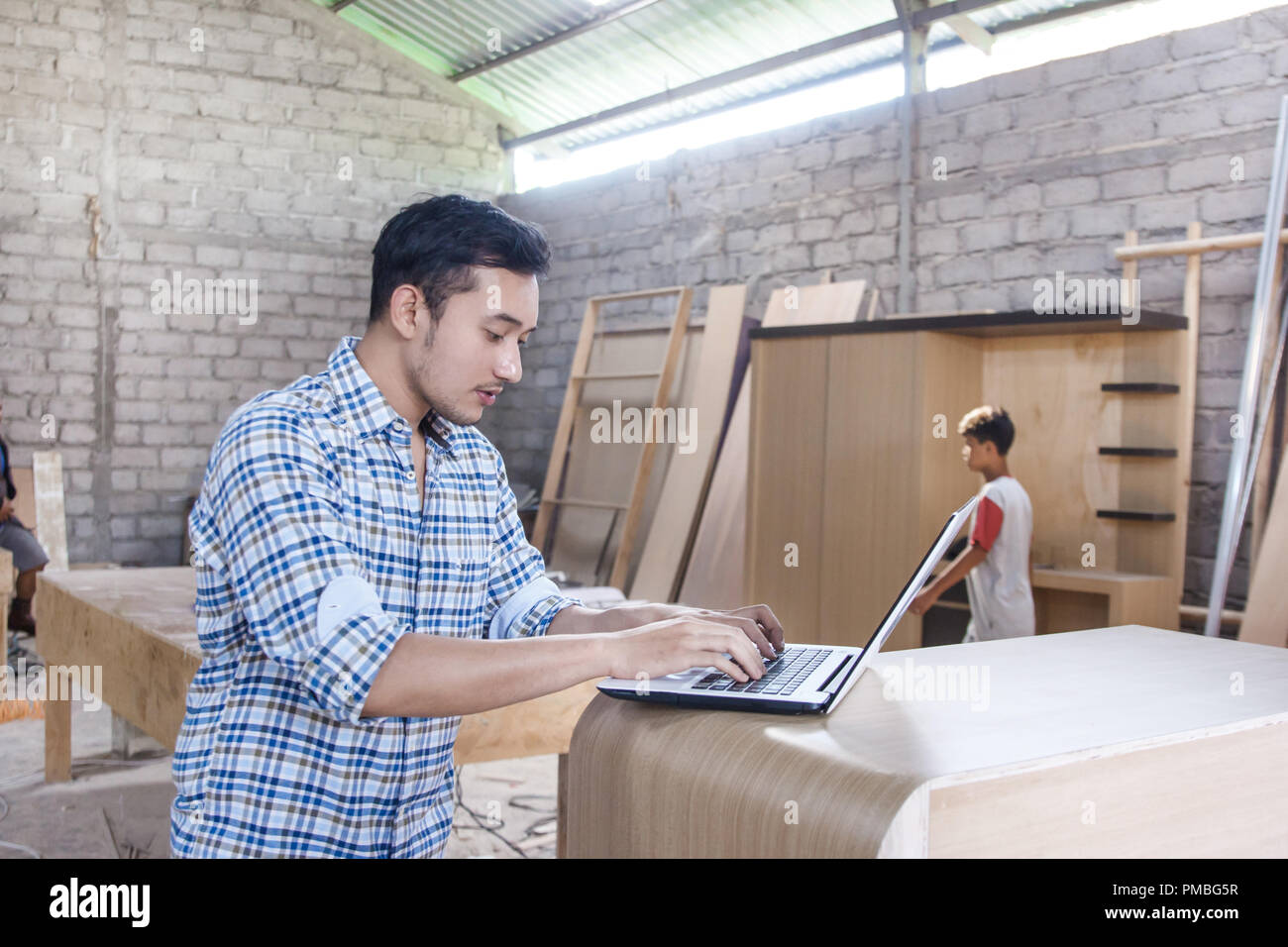 young carpenter working on his laptop Stock Photo