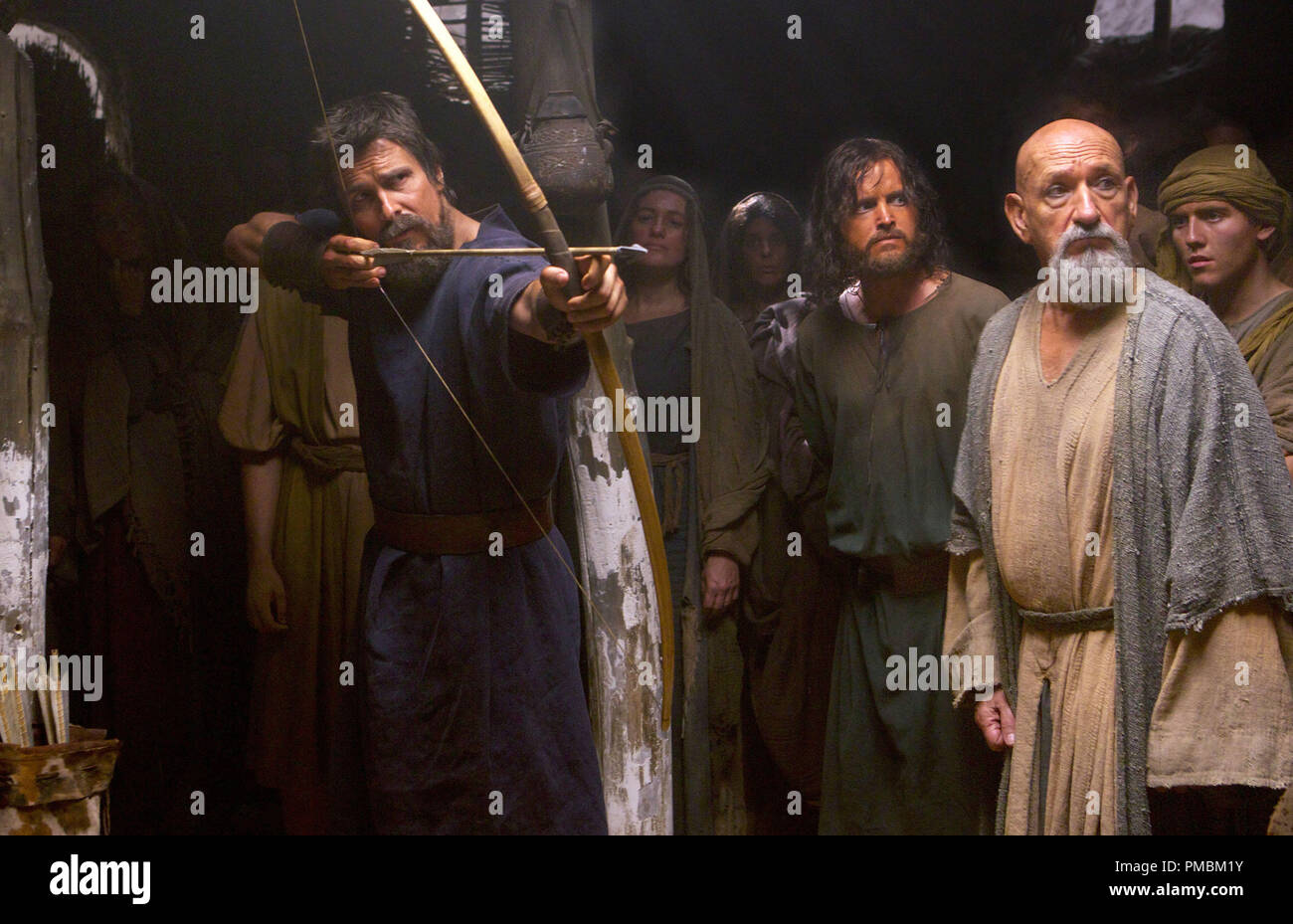 Exodus: Gods and Kings (2014) Moses (Christian Bale) displays his prowess with a bow and arrow, as Joshua (Aaron Paul, center) and Nun the scholar (Ben Kingsley) watch. Stock Photo