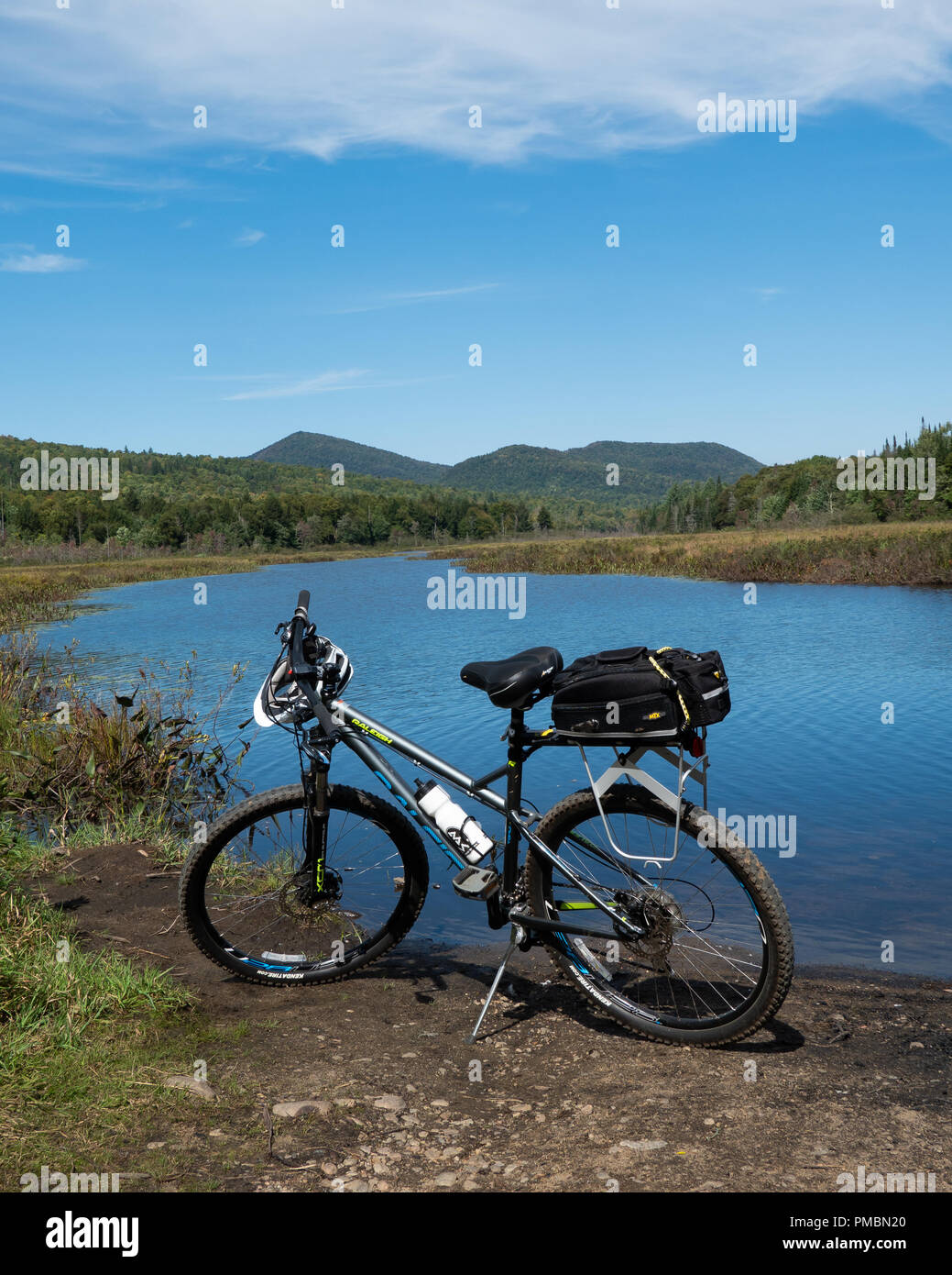 A gray Raleigh mountain bicycle parked on the shore of the Kunjamuk River in the Adirondack Mountains, NY, with a view of the river and wilderness. Stock Photo