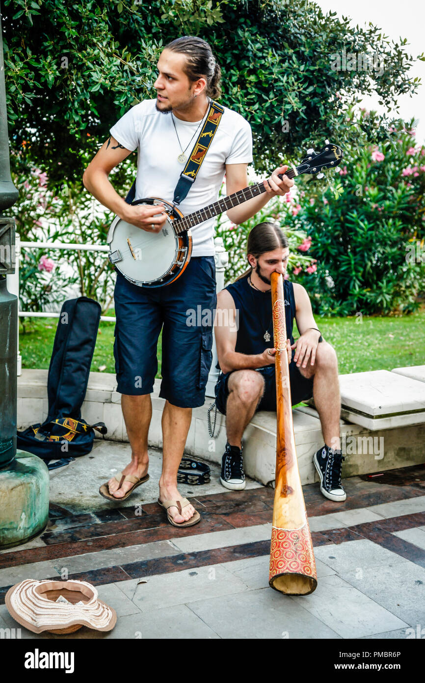 Two guys playing a banjo and a didgeridoo busking by the park in Opatija, Croatia Stock Photo