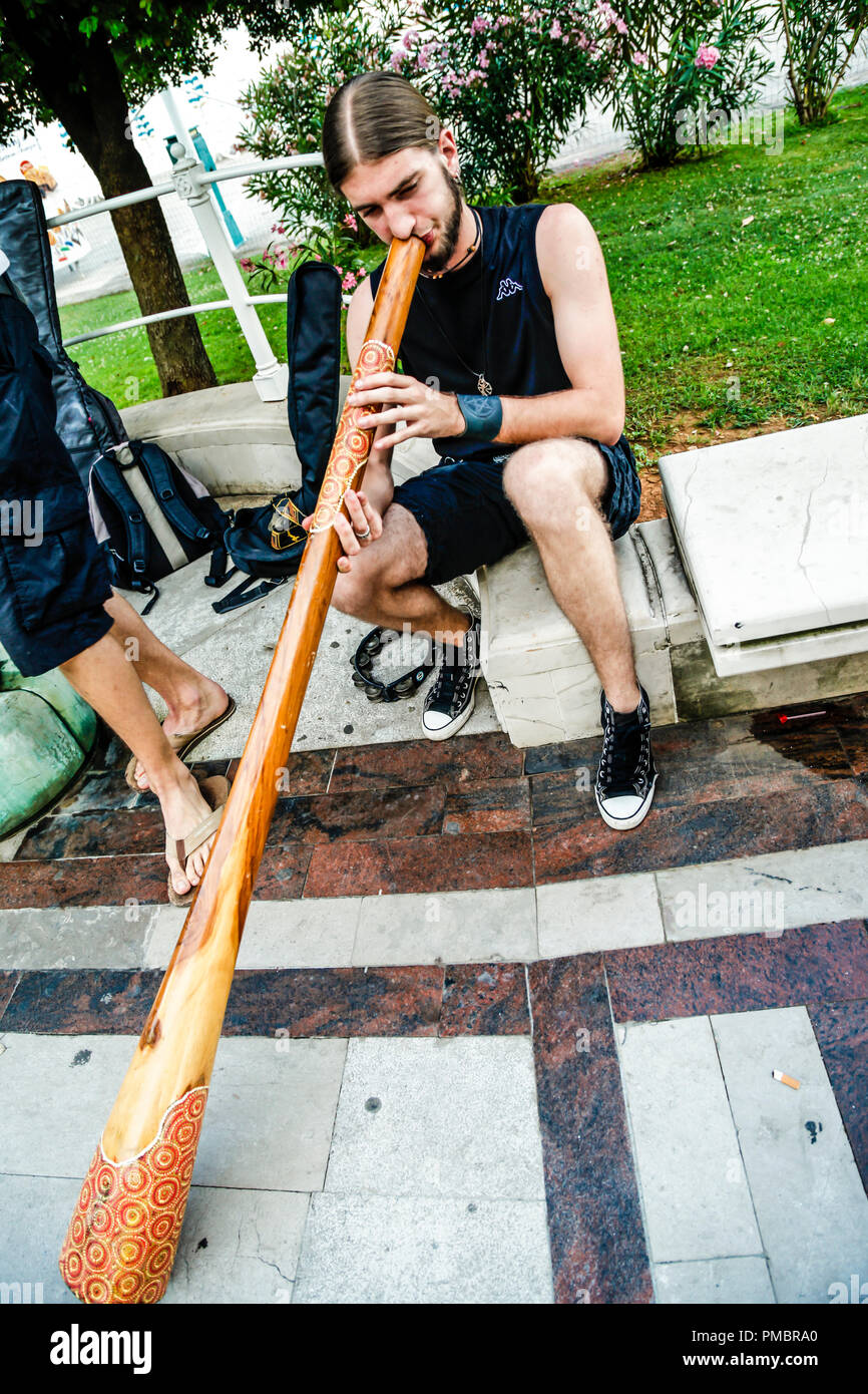 Man playing the didgeridoo with a group of buskers by the park in Opatija, Croatia Stock Photo