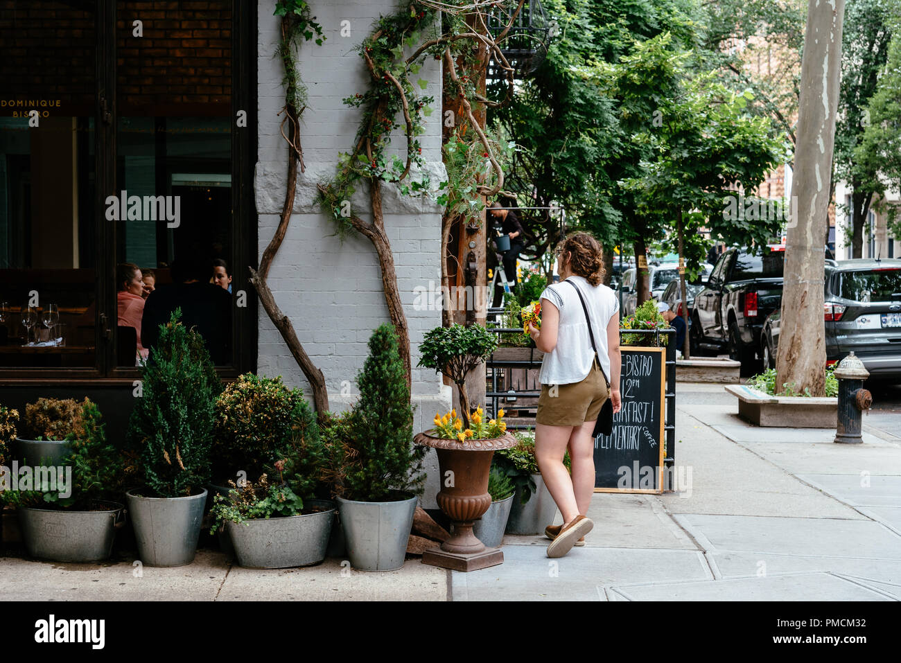 New York City, USA - June 22, 2018: Woman at fashionable restaurant in the corner of Gay Street with Christopher Street in Greenwich Village Stock Photo