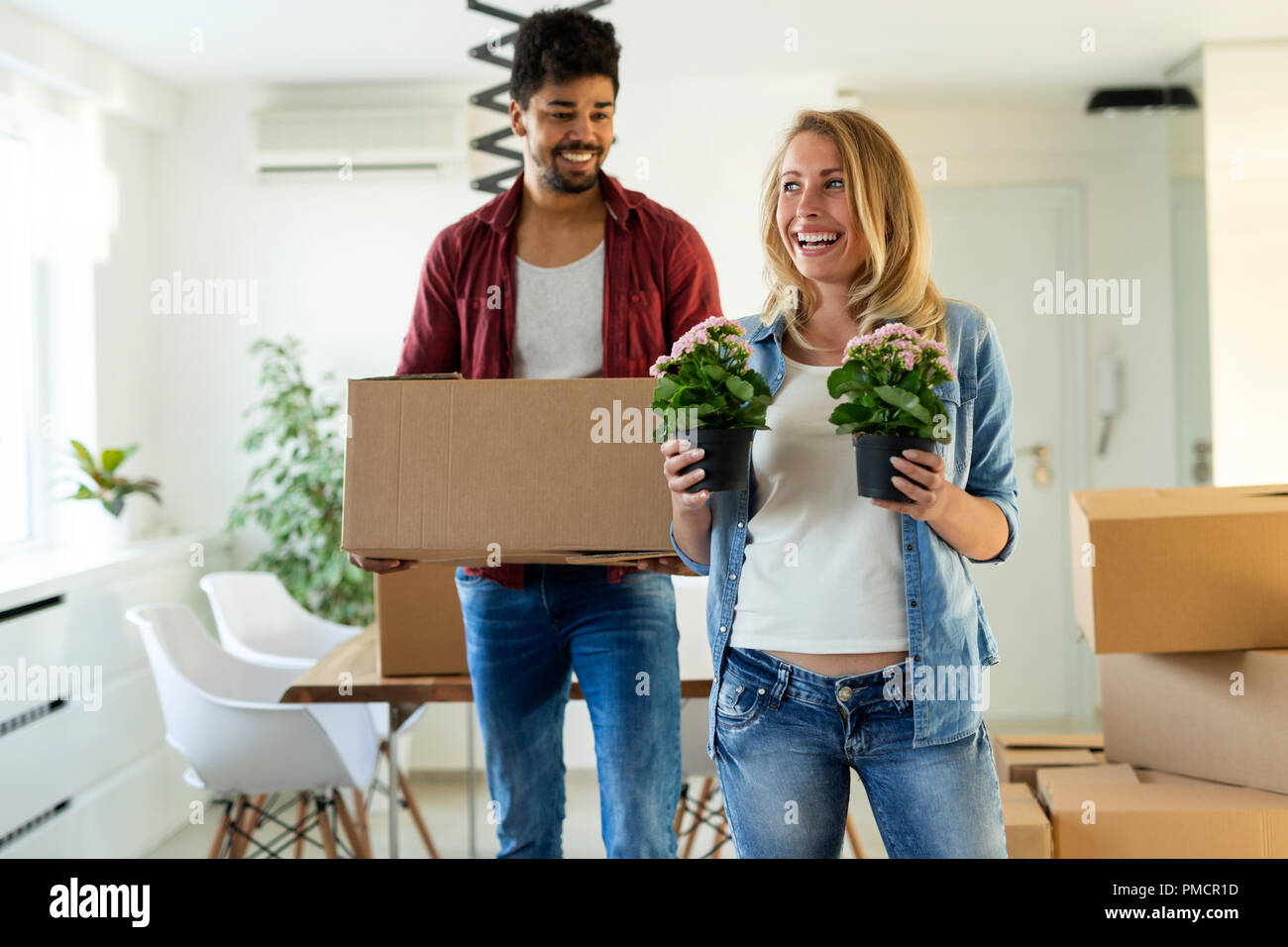 Young happy couple moving in new home and unpacking boxes Stock Photo ...