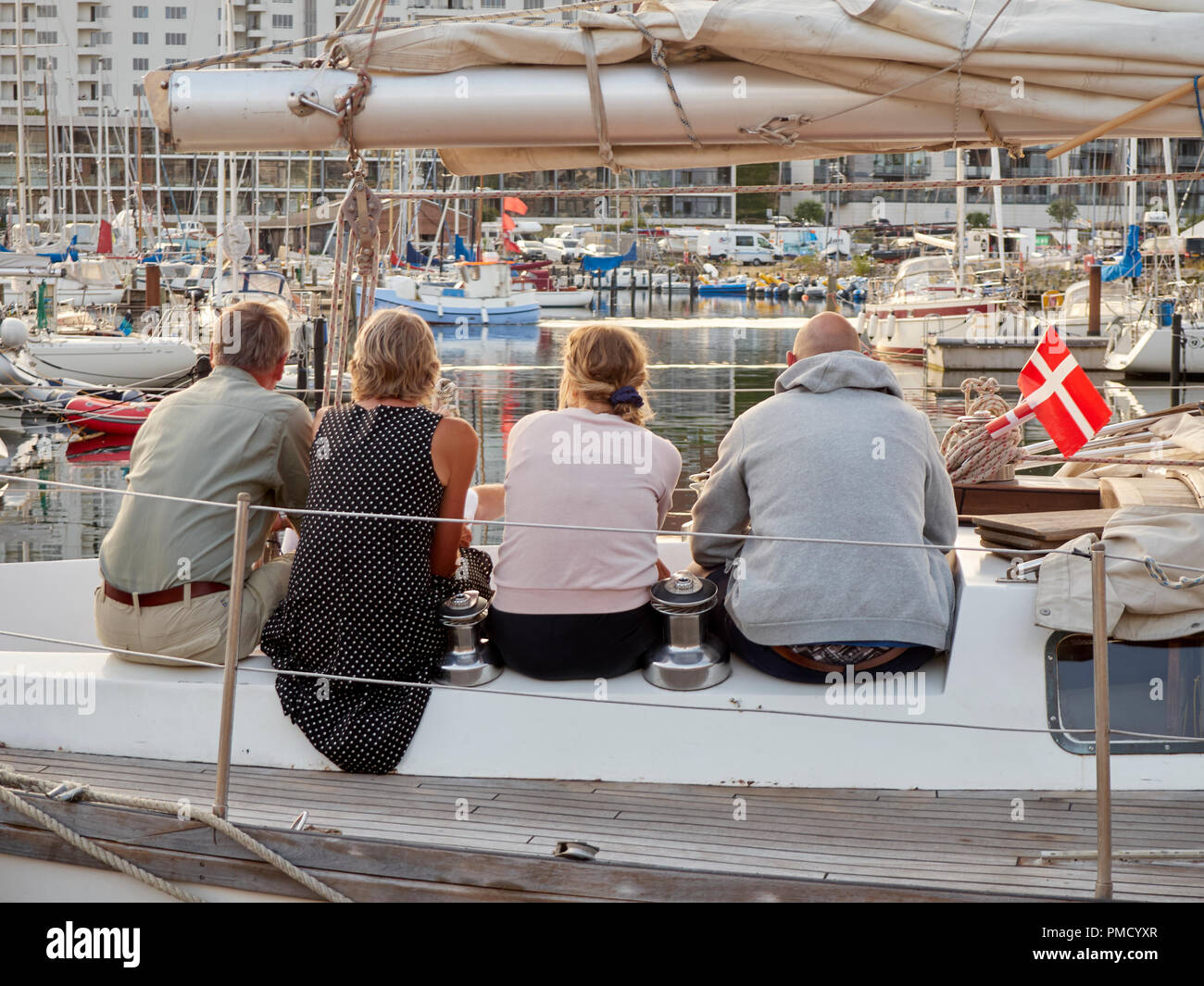 4 people with their backs to the camera, sitting on boat Stock Photo