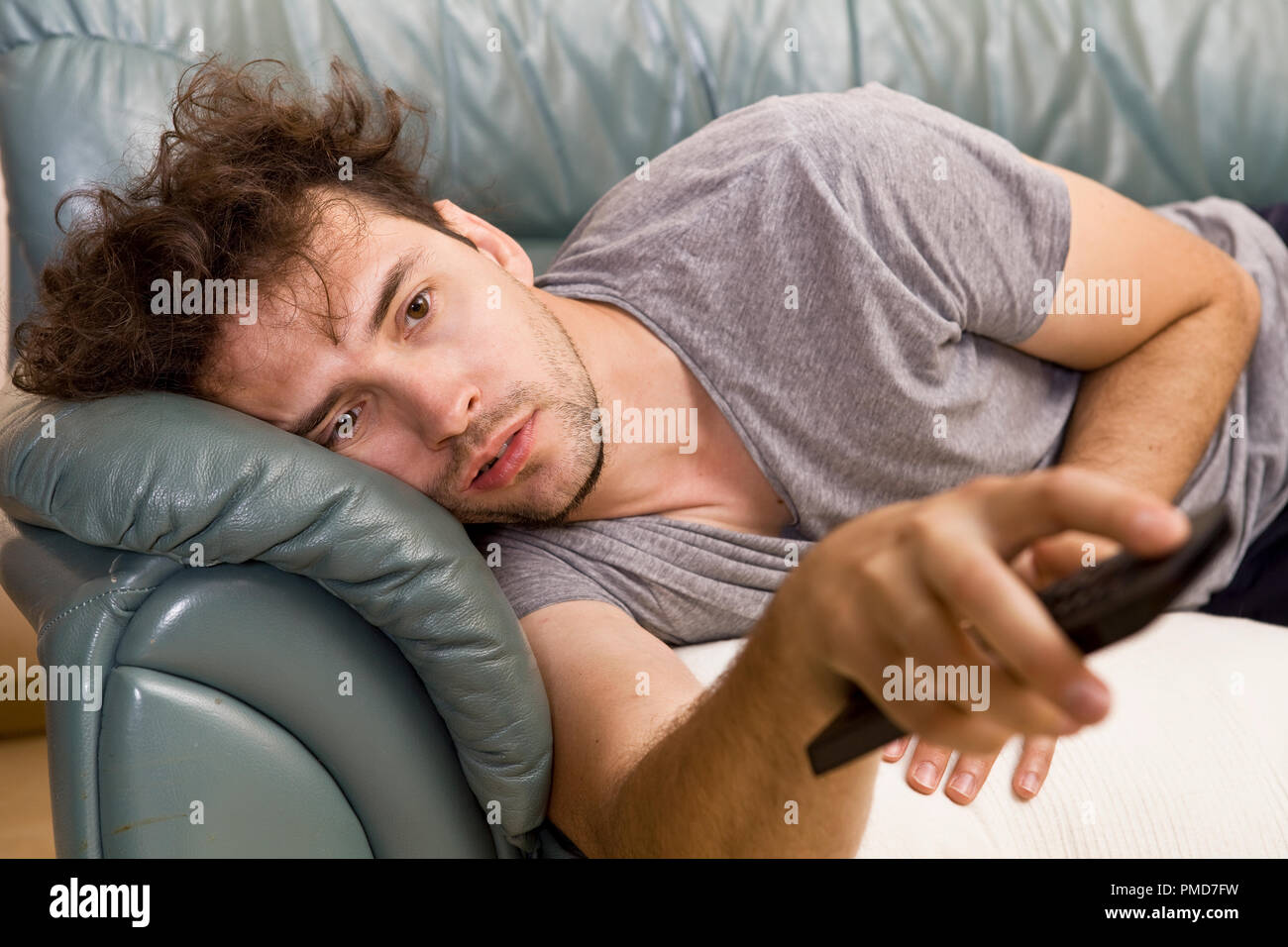 A young man watches television and changes channels while relaxing Stock Photo