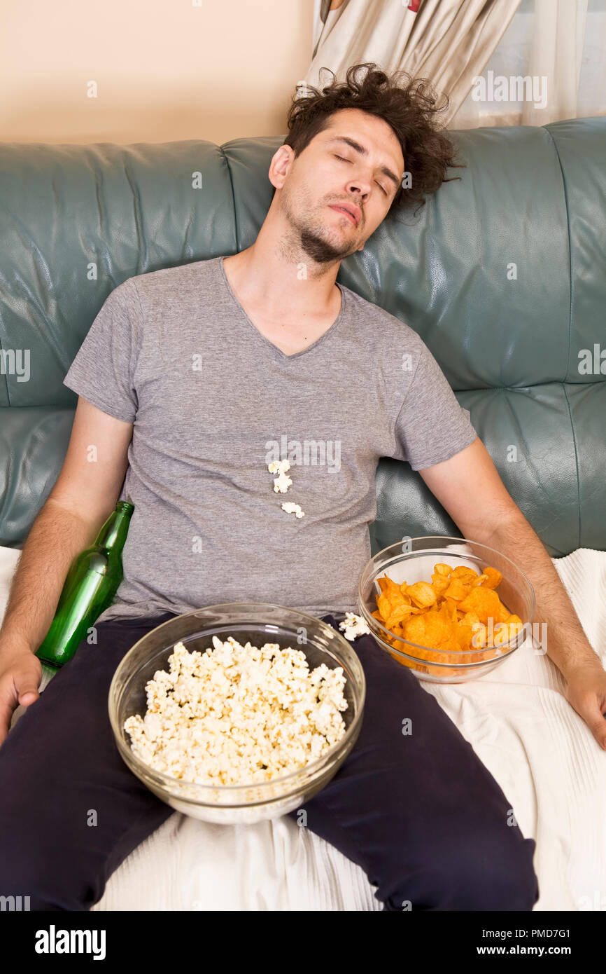 A man sleeping on a couch in a mess of junk food Stock Photo Alamy