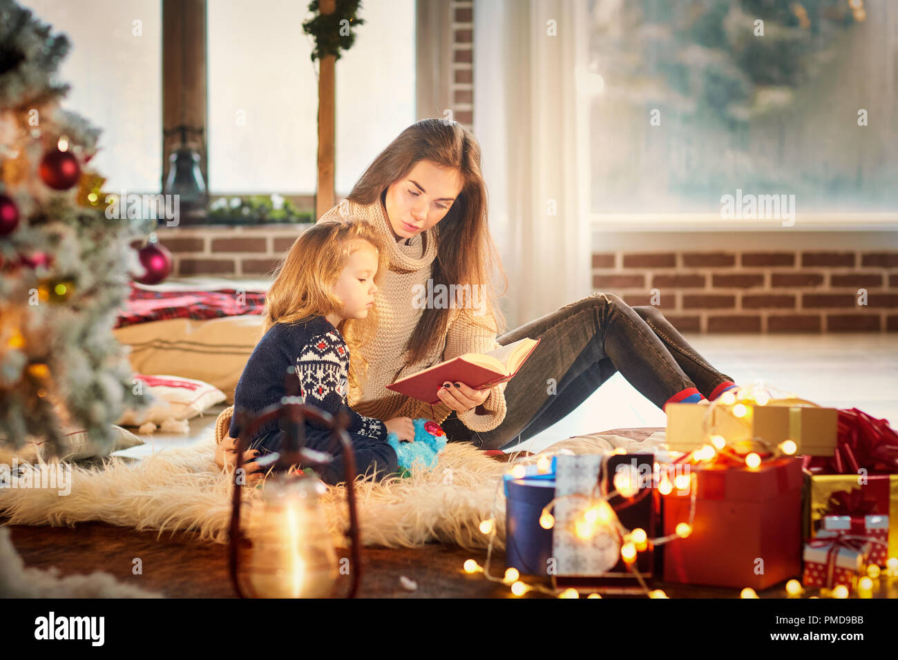 Mom and children are reading a book on Christmas Day. Stock Photo