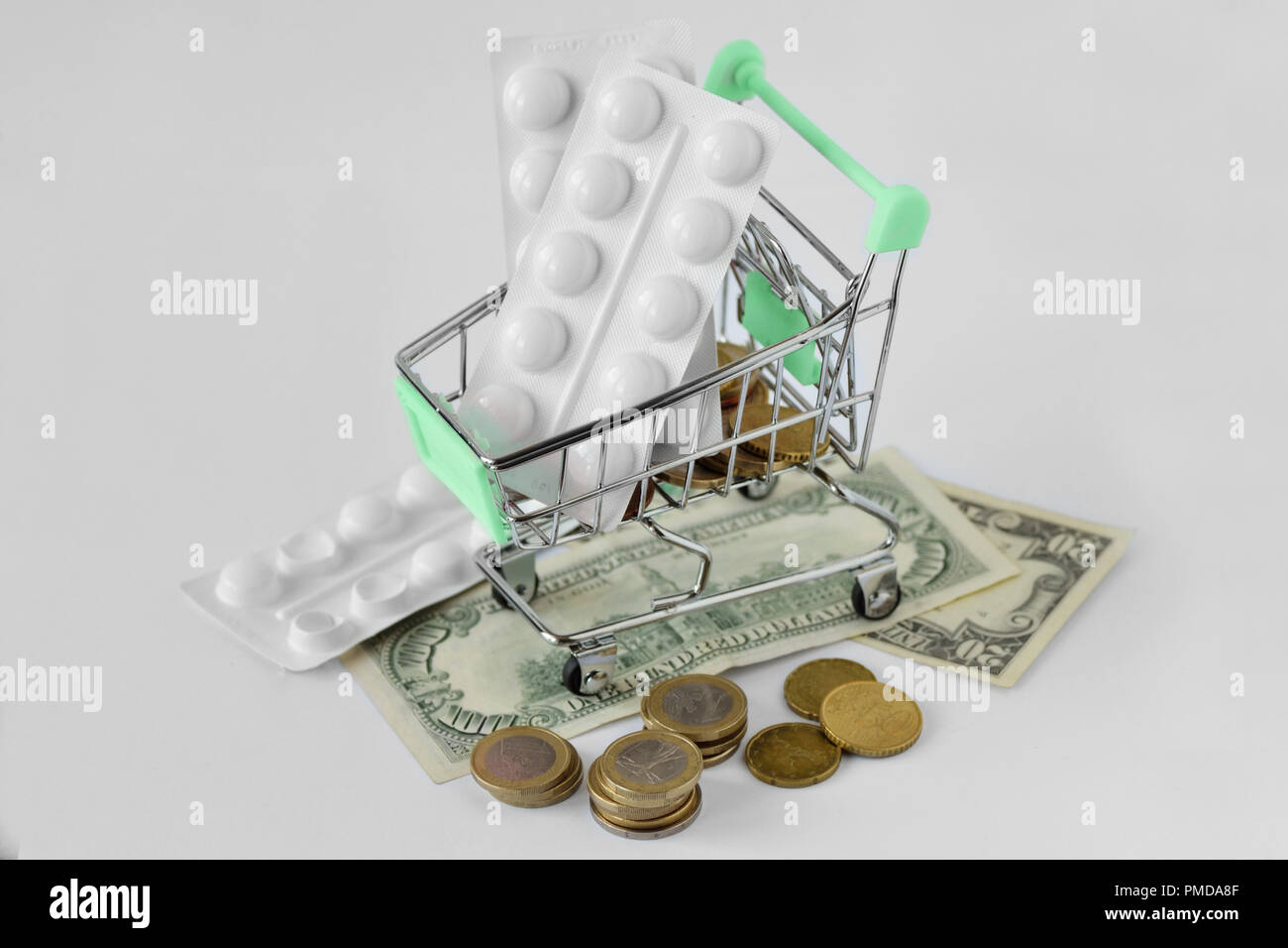 Shopping cart with medicine pills on money - Pharmaceutical cost concept Stock Photo