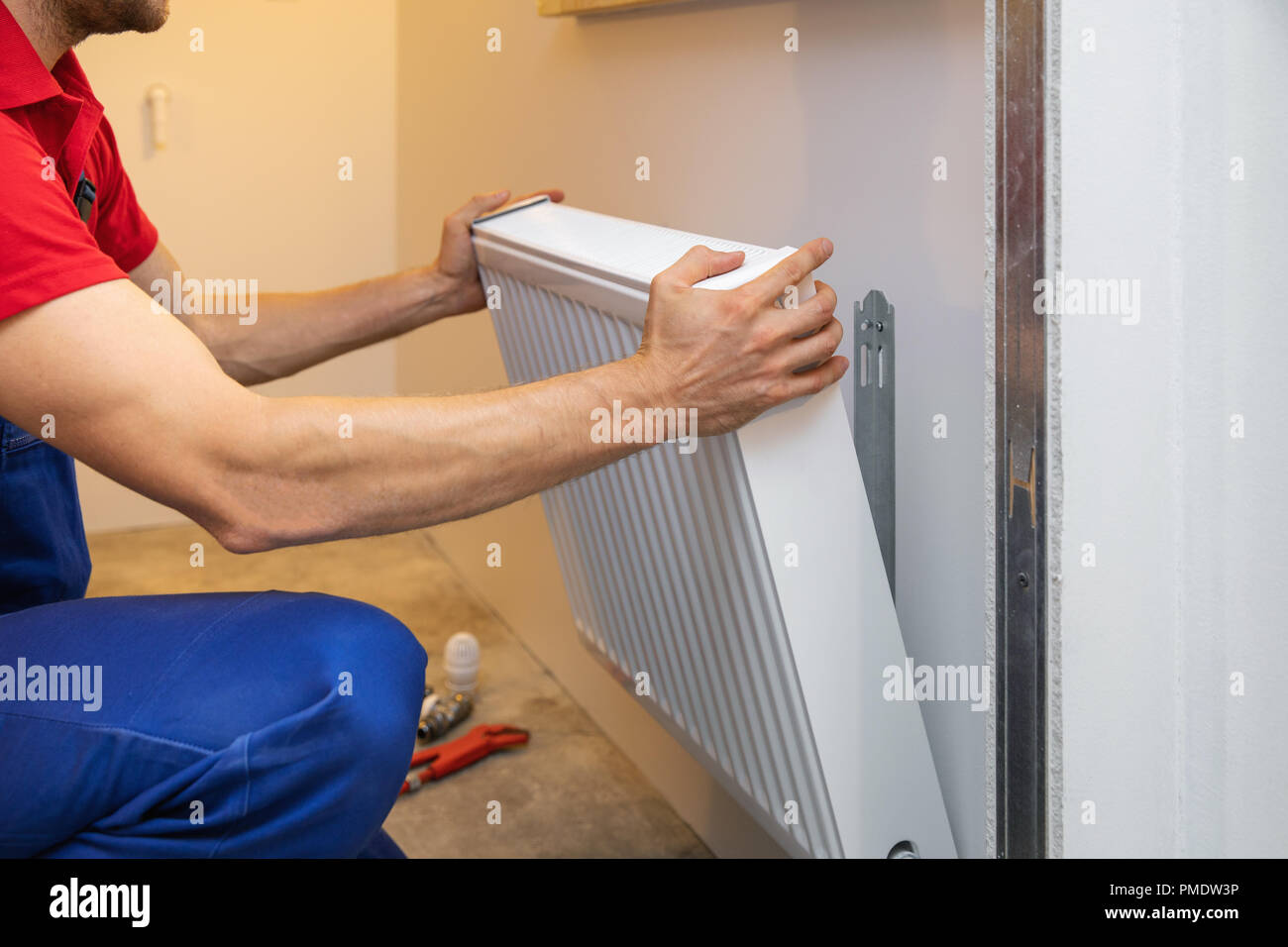man installing room heater on the wall Stock Photo