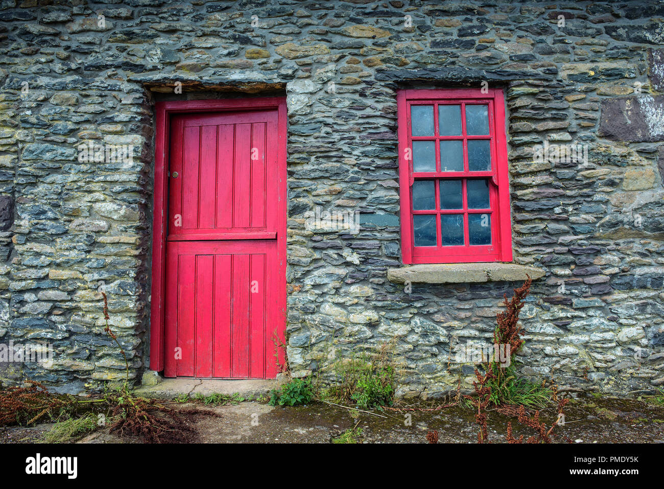 A vintage door and window on a facade of an old cottage built of stones in Ireland Stock Photo