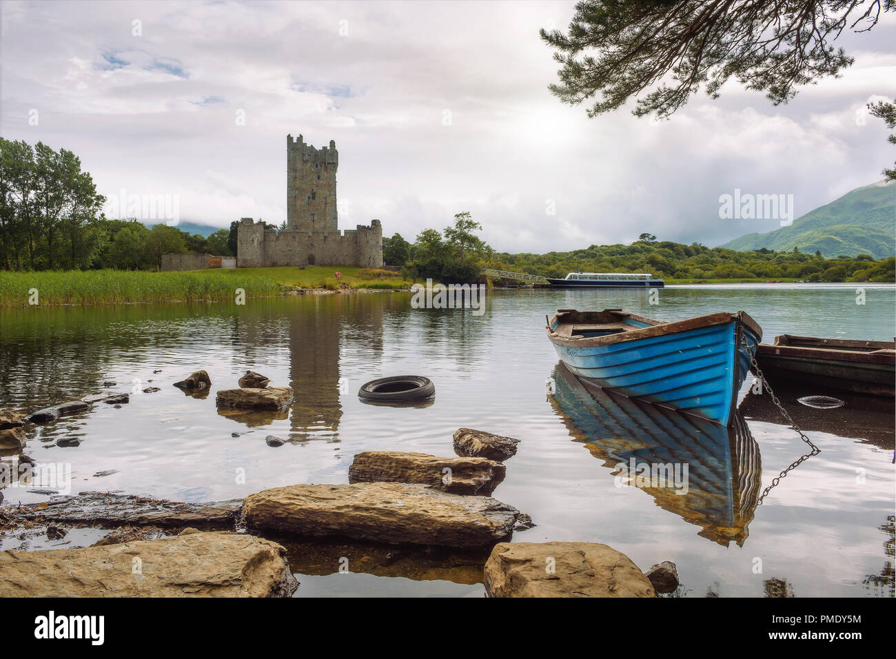 Ross Castle ruins and the Lough Leane lake with a blue boat in the foreground in the Killarney National Park, Ireland Stock Photo
