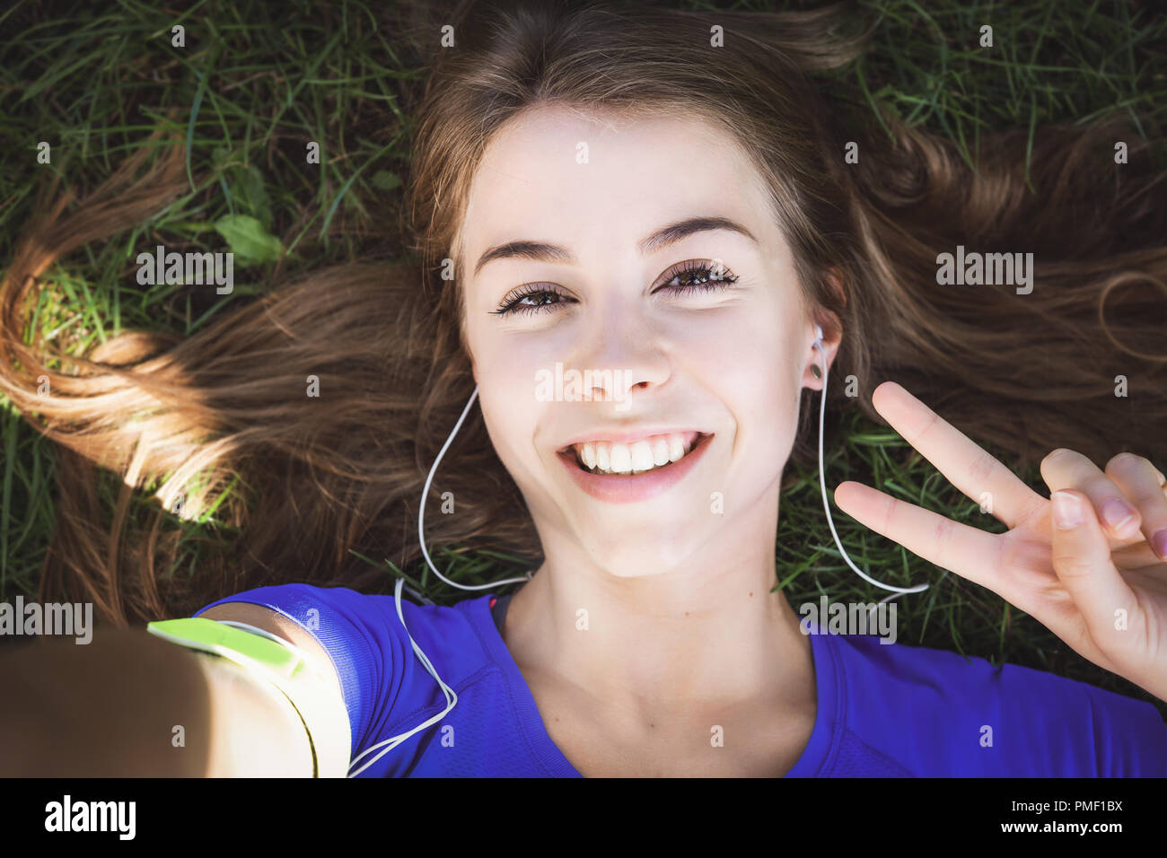 Beautiful fitness girl taking a selfie photo and showing victory gesture while resting after outdoors workout (vintage effect) Stock Photo