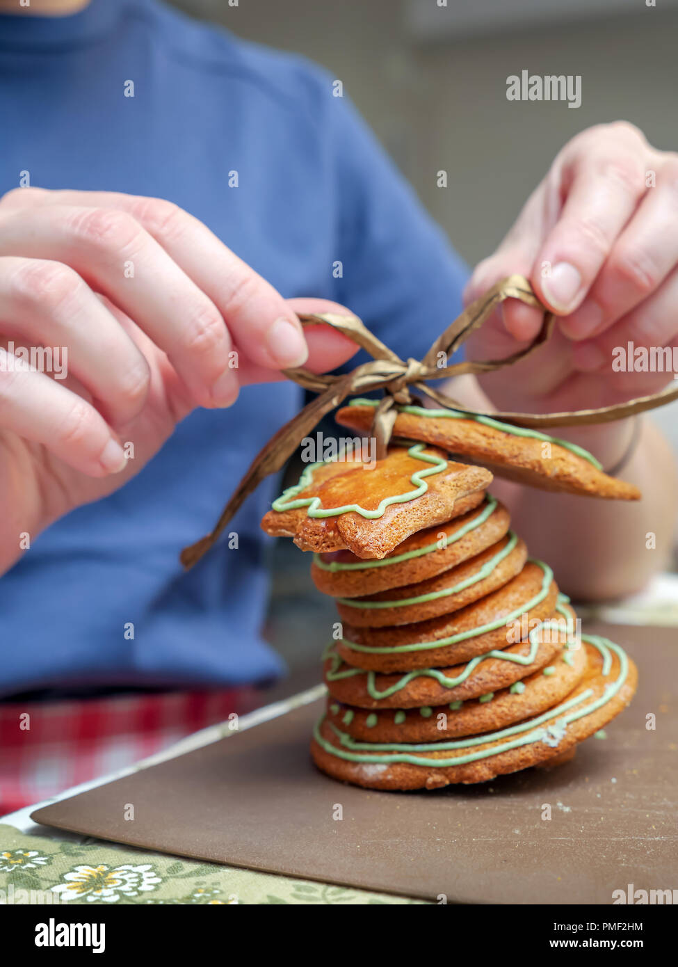 Closeup of young female hands assembling Christmas bell from gingerbread shaped cookies Stock Photo