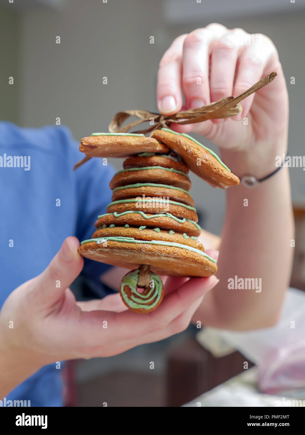 Closeup of young female hands showing Christmas bell assembled from gingerbread shaped cookies Stock Photo