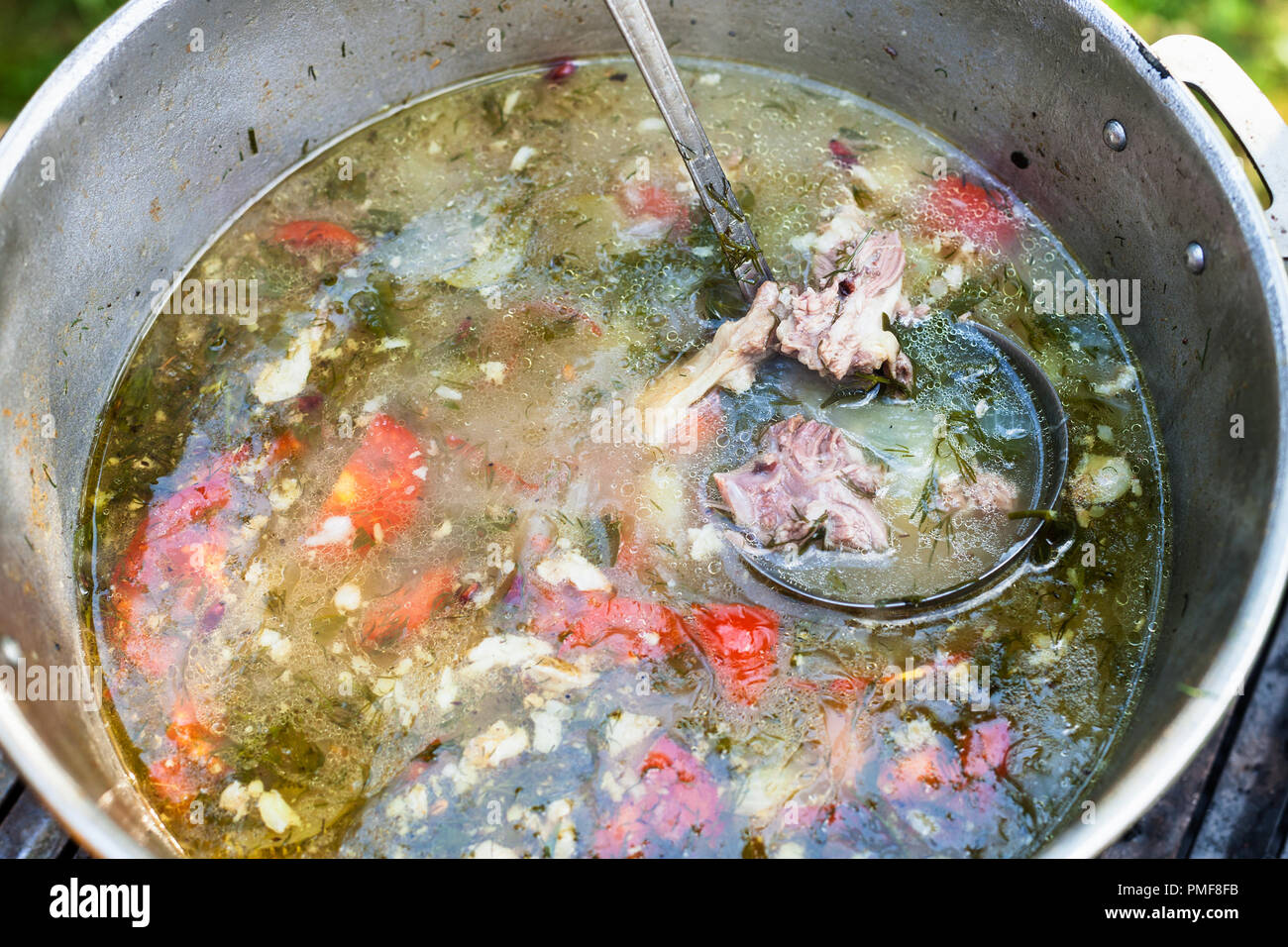 top view of cooking central asian shurpa (soup from meat and large-sliced vegetables) in pot outdoors Stock Photo