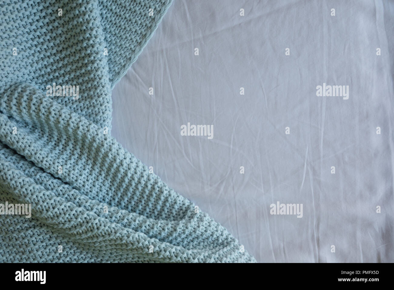 Handmade blue knitted wool blanket on bed, texture background Stock Photo