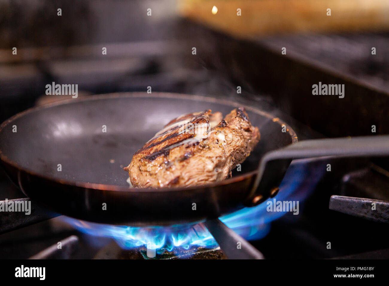 Chef seasoning beef on pan while cooking in restaurant kitchen Stock