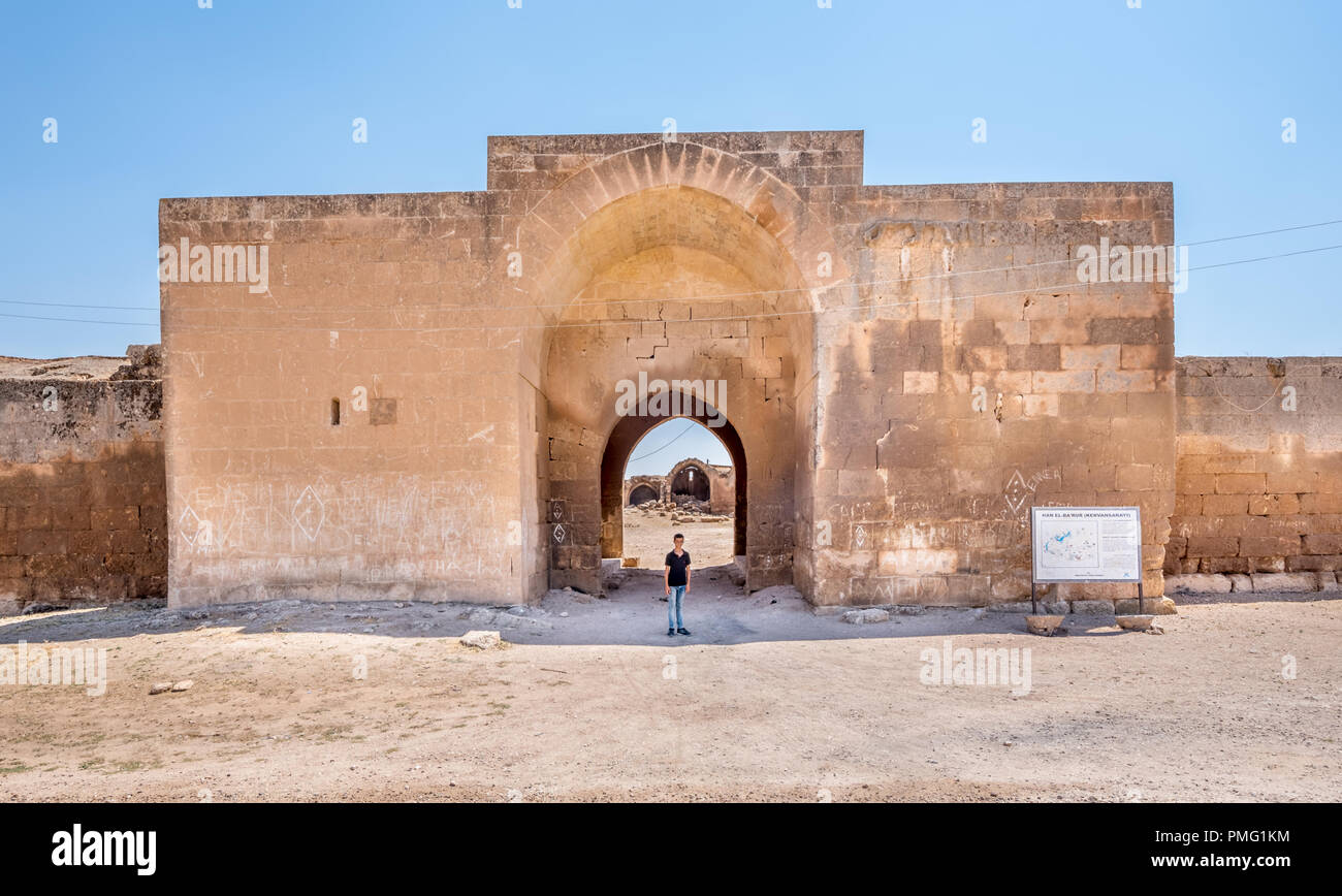 Unidentified boy stands in front of Han El Ba'rur,a Seljuk caravanserai in Harran,Sanliurfa,Turkey.20 July 2018 Stock Photo