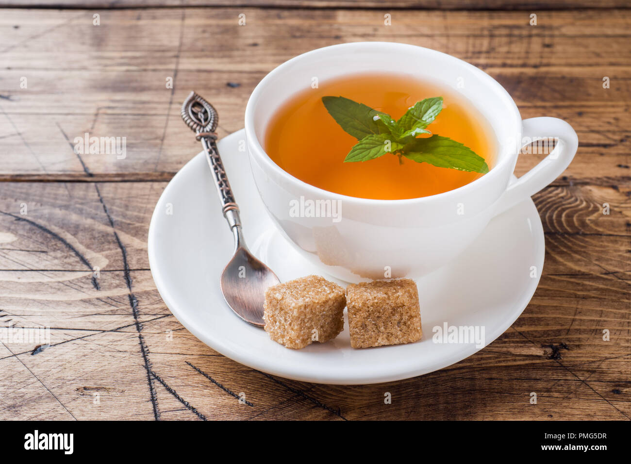 Cup of hot tea with mint and brown sugar on a wooden table Stock Photo -  Alamy, image size:1300x956