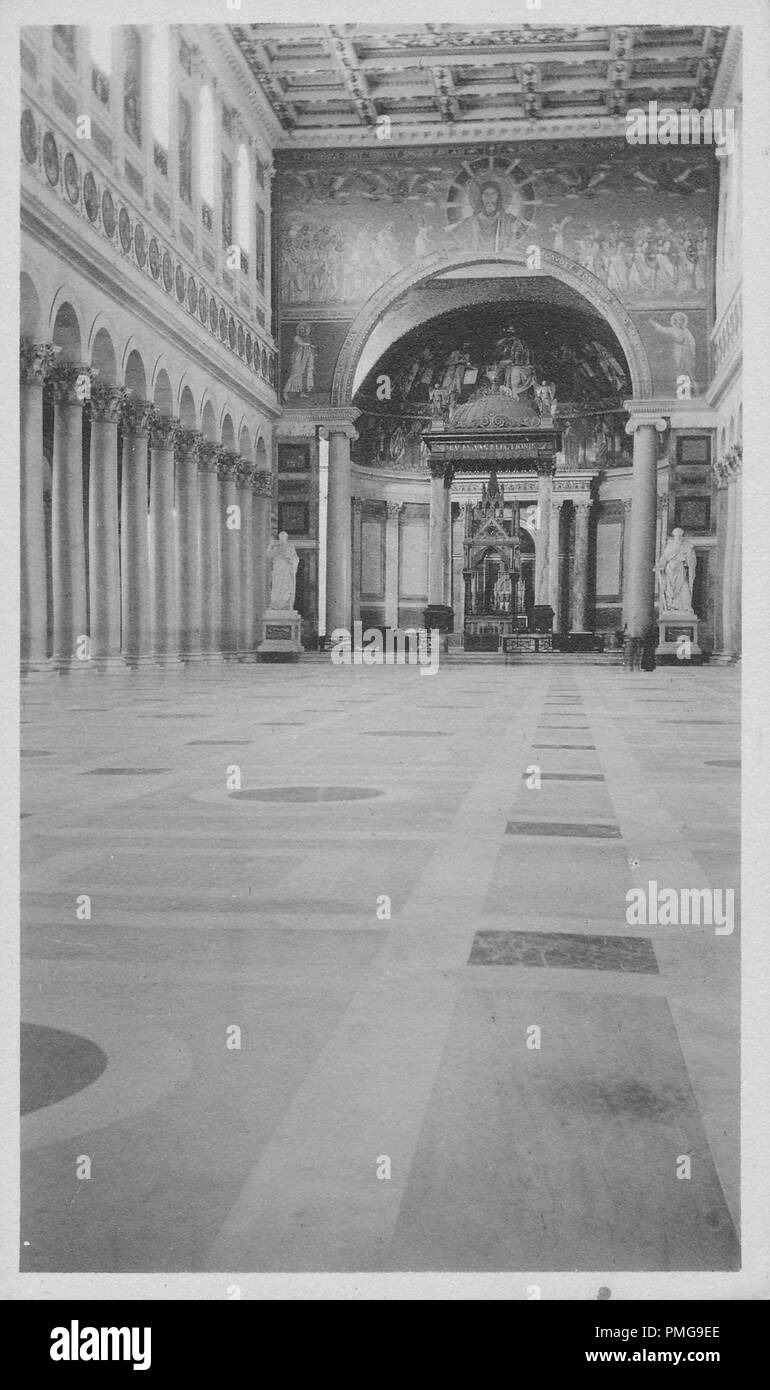 Black and white photograph on cardstock, with an image of the interior of a Catholic church, shot from a low angle, looking toward the apse and altar, with a small gothic altar, with crocket capitals, standing beneath an ornate tabernacle, carried on four columns, with religious mosaics in the apse, entablature, and superior wall section, a coffered ceiling, a collonade of Corinthian columns visible at left, and an inlaid marble floor, likely collected as a tourist souvenir during a trip to Northern Europe (likely in a region of the Upper Rhine, near the borders of Germany, Switzerland, and Fr Stock Photo