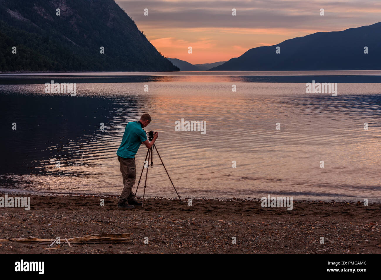 The photographer shoots a beautiful pink sunset over the lake and mountains Stock Photo