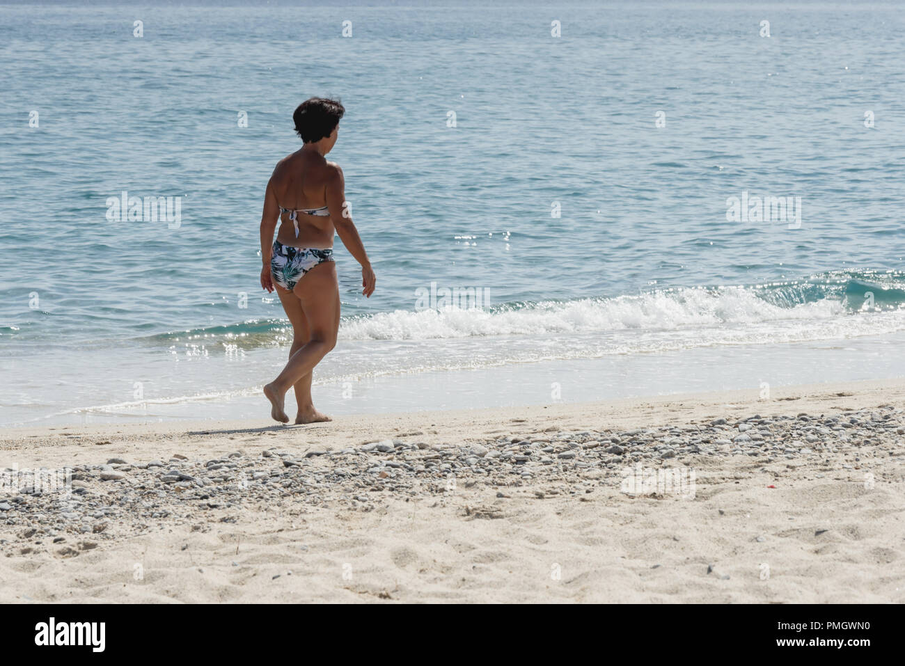 Italy Calabria Middle-aged woman at the seaside walking on the beach Stock Photo