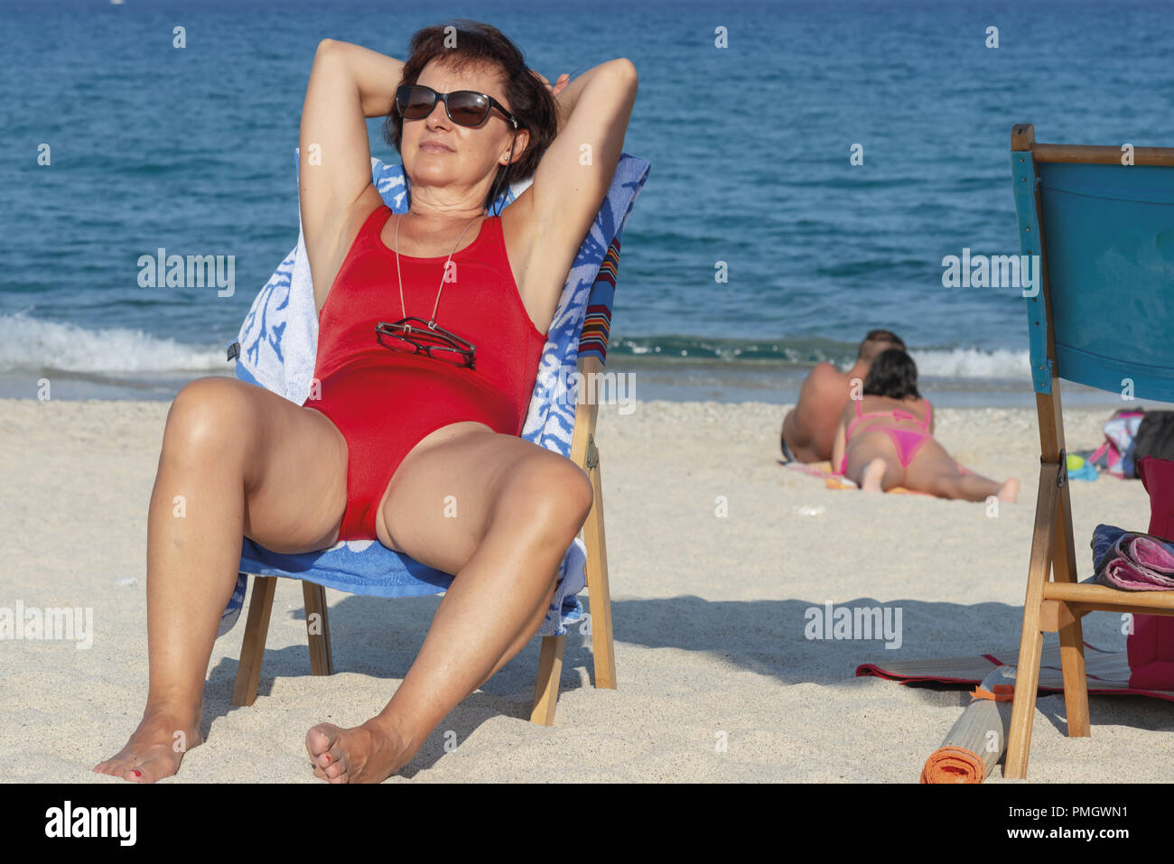 Italy Calabria Middle-aged woman at the sea sitting on a tanning bed Stock Photo