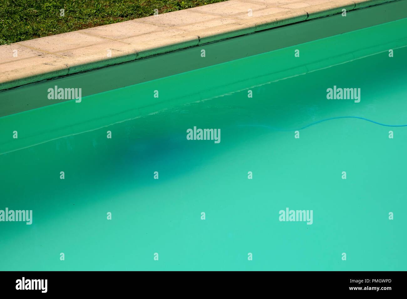Swimming pool maintenance - An automatic robot pool cleaner can just be seen on the bottom of a cloudy swimming pool removing debris and algae. Stock Photo