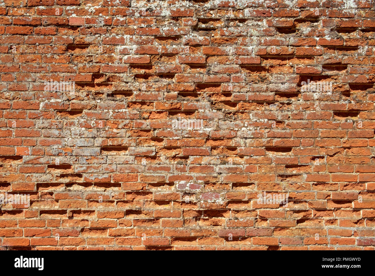 Very old weathered, damaged, badly repaired red brick wall close up full frame background Stock Photo