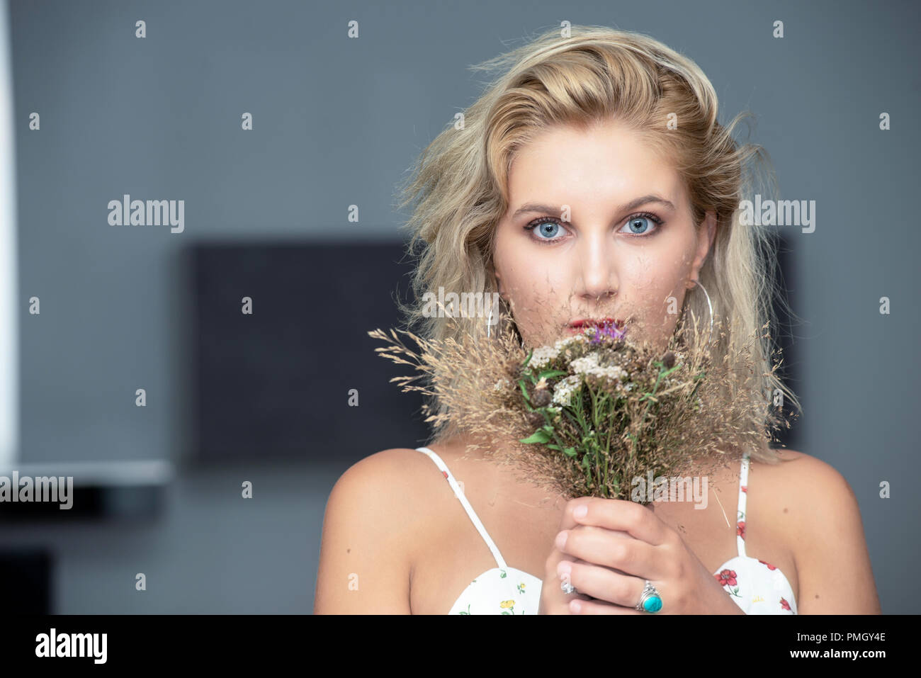 portrait of a beautiful young blonde woman with a bouquet of flowers ...