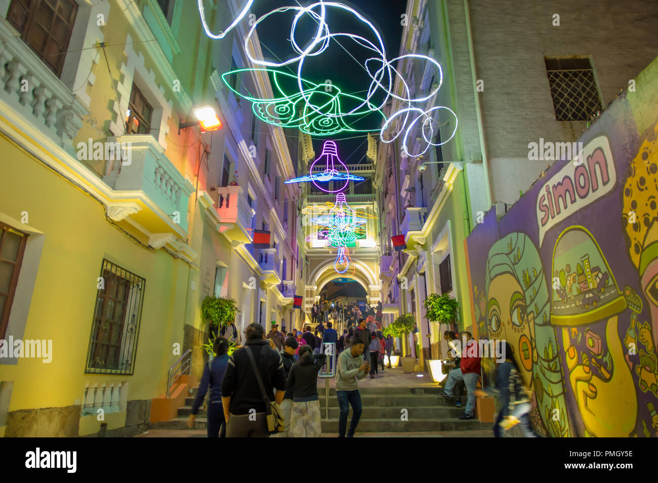 QUITO, ECUADOR- AUGUST, 15, 2018: Unidentified people walking in a tight street during a spectacle of lights projected on the walls with some illuminated figures during the Quito light festival Stock Photo