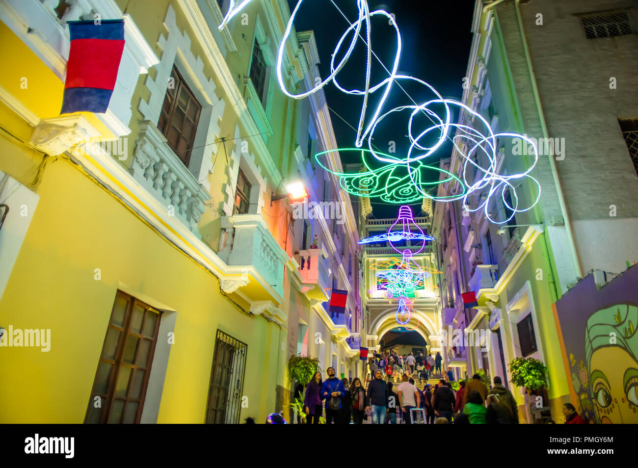 QUITO, ECUADOR- AUGUST, 15, 2018: Crowd of people walking in a tight street during a spectacle of lights projected on the walls with some illuminated figures during the Quito light festival Stock Photo