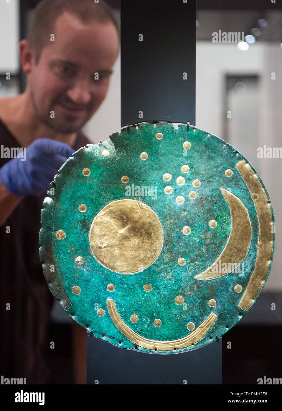 18 September 2018, Berlin: The exhibit designer Falk Lehmann from the company 'Fißler und Kollegen' from Leipzig installs the Nebra Sky Disk in a showcase with a colleague in the Martin-Gropius-Bau. The Bronze Age disc will be on display from 21.09.2018 together with about 1000 archaeological finds in the exhibition 'Moving Times. Archaeology in Germany'. Photo: Soeren Stache/dpa Stock Photo