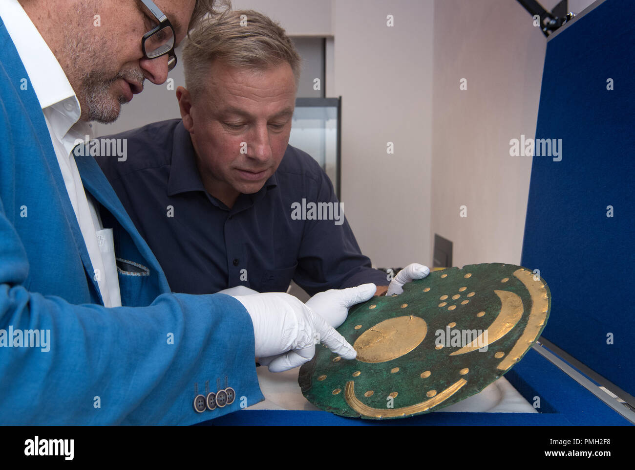 18 September 2018, Berlin: Harald Meller (l), Director of the State Office for the Preservation of Monuments and Archaeology in Saxony-Anhalt, and Matthias Wemhoff, Director of the Berlin Museum for Prehistory and Early History of the State Museums look at the Nebra Sky Disc in the Martin-Gropius-Bau. The Bronze Age disc will be on display from 21.09.2018 together with about 1000 archaeological finds in the exhibition 'Moving Times. Archaeology in Germany'. Photo: Soeren Stache/dpa Stock Photo