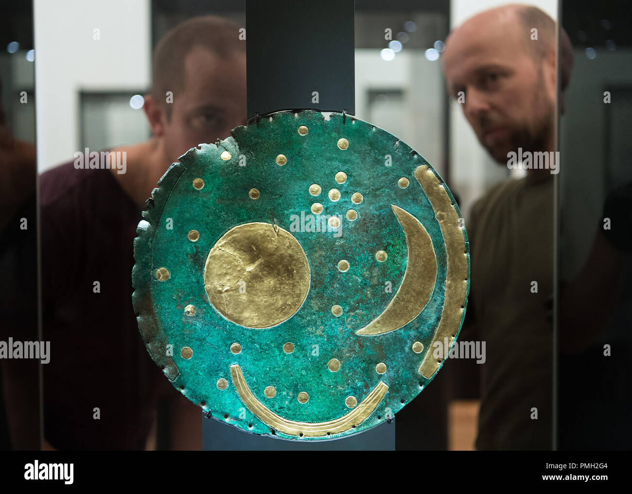 18 September 2018, Berlin: Exhibit designer Thomas Fißler (r) and Falk Lehmann of 'Fißler und Kollegen' from Leipzig install the Nebra Sky Disc in a showcase in the Martin-Gropius-Bau. The Bronze Age disc will be on display from 21.09.2018 together with about 1000 archaeological finds in the exhibition 'Moving Times. Archaeology in Germany'. Photo: Soeren Stache/dpa Stock Photo