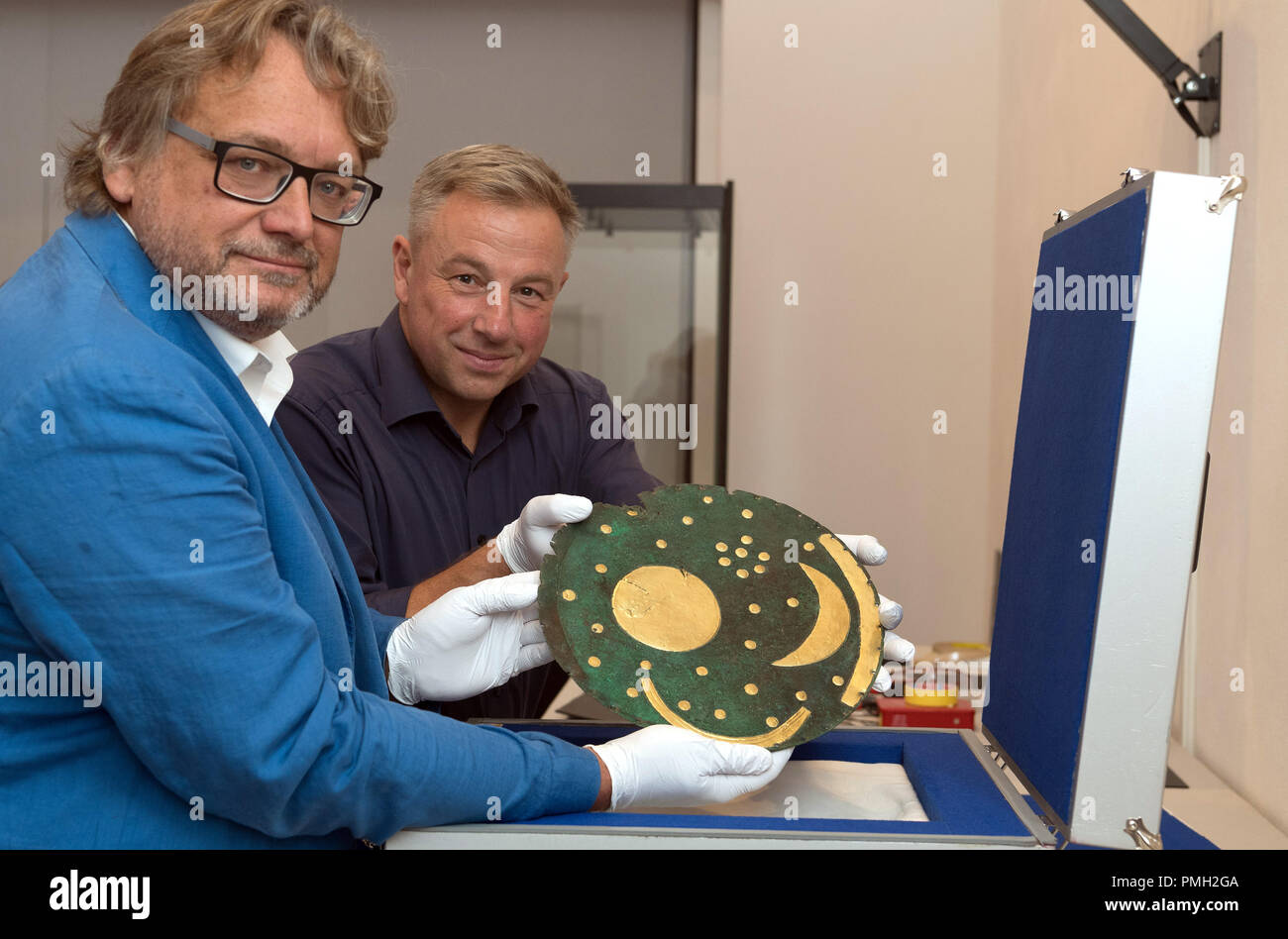 18 September 2018, Berlin: Harald Meller (l), Director of the State Office for the Preservation of Monuments and Archaeology in Saxony-Anhalt, and Matthias Wemhoff, Director of the Berlin Museum for Prehistory and Early History of the National Museums have taken the Nebra Sky Disc from a special transport box in the Martin-Gropius-Bau. The Bronze Age disc will be on display from 21.09.2018 together with about 1000 archaeological finds in the exhibition 'Moving Times. Archaeology in Germany'. Photo: Soeren Stache/dpa Stock Photo