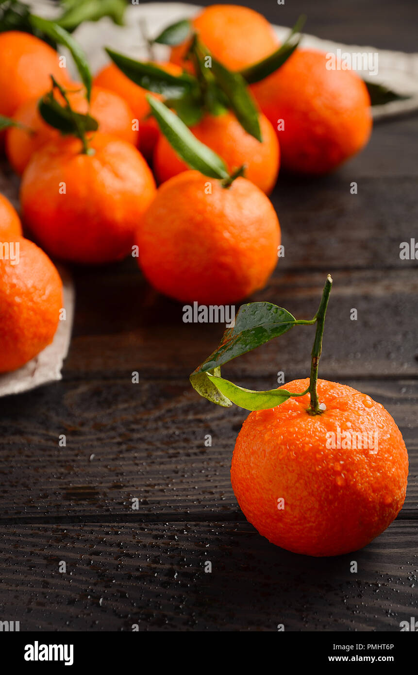 Fresh Tangerine Clementines with Leaves on Dark Wooden Table. Stock Photo