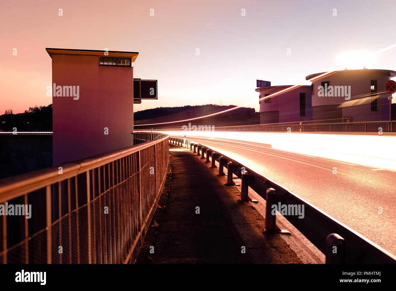 Long exposure shot of the Schiffenen dam in the county of Fribourg, in Switzerland, with vehicle light trails on the side Stock Photo