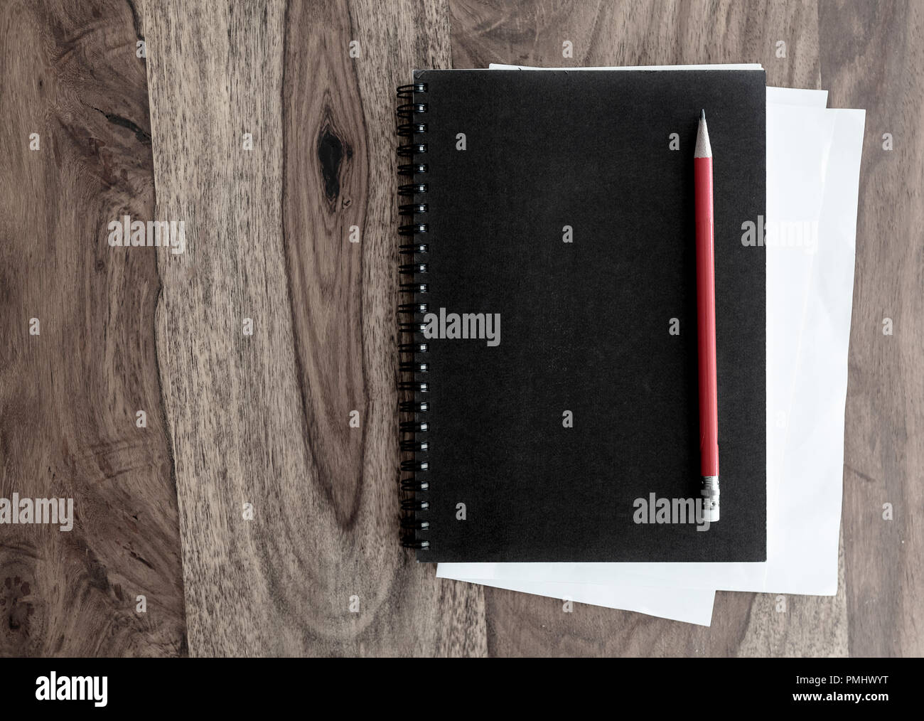 black spiral notebook and pen on wooden table Stock Photo