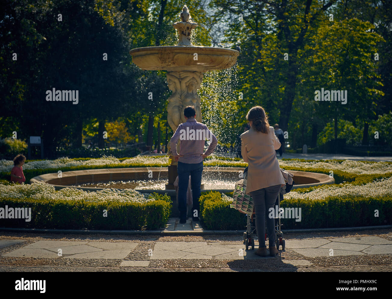 Parents with kids standing outdoors in front of fountain spending weekend together Stock Photo